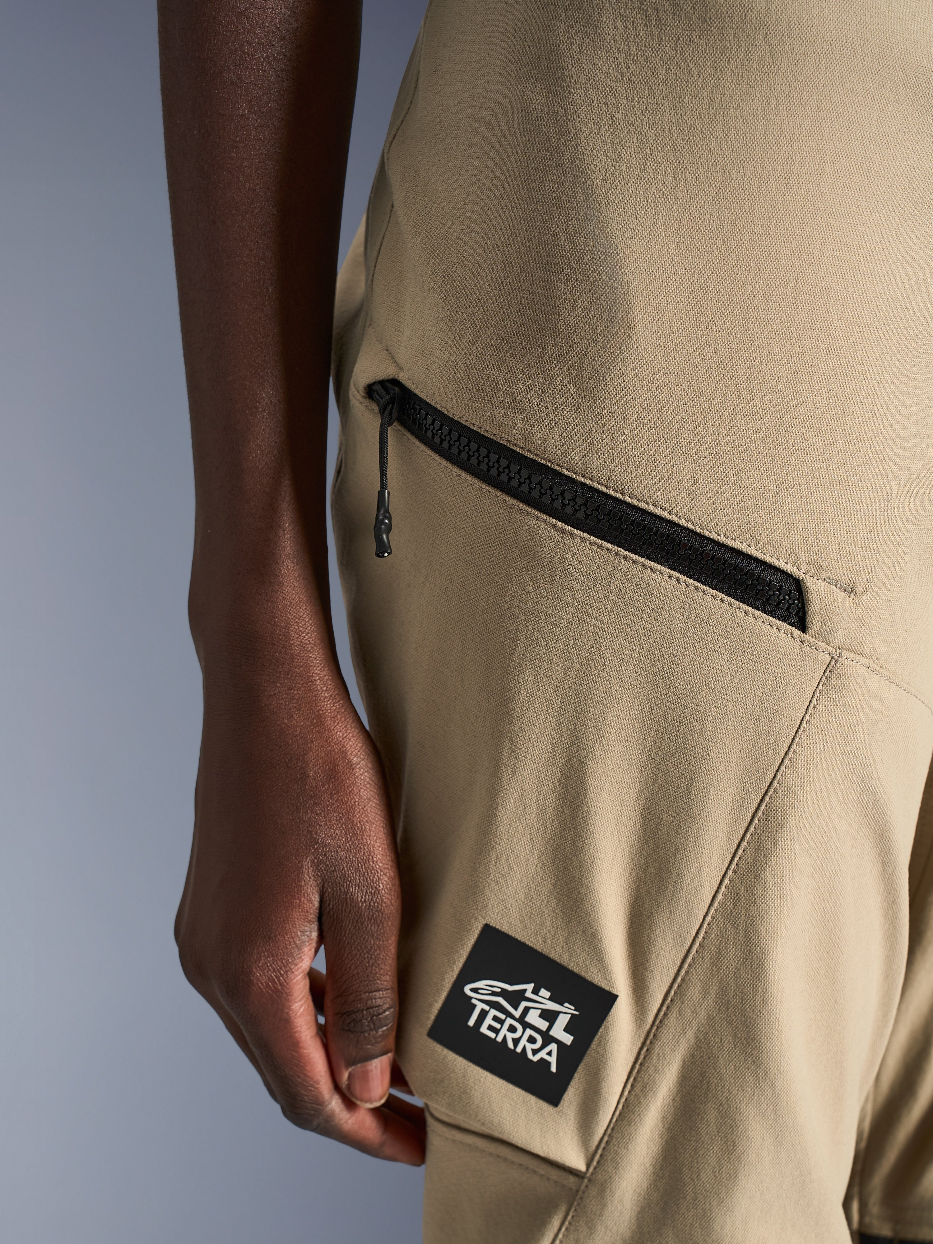 Alpinestars Stella Flex-AST Explorer Hose, Motorradhose für Damen, Sand, Detailaufnahme der Cargo-Tasche mit Reißverschluss und schwarzem ALL TERRA Logo-Aufnäher, strapazierfähige Ripstop-Textilkonstruktion für Adventure-Touren