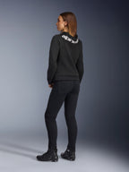 Alpinestars Daisy V3 Damen-Motorradjeans, Damen-Motorradhose, Rinse Black, Rückansicht zeigt Slim-Fit-Passform und hohen Bund hinten, kombiniert mit einem schwarzen Alpinestars-Hoodie und Motorradstiefeln für einen urbanen Motorrad-Look