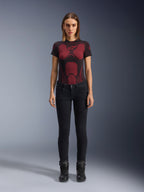 Alpinestars Daisy V3 Damen-Motorradjeans, Rinse Black, Slim-Fit Motorradhose, getragen von einem Model mit einem rot-schwarz gemusterten technischen T-Shirt und schwarzen Motorradstiefeln, lässige urbane Fahrausrüstung mit femininer Silhouette und High-Waist-Design.