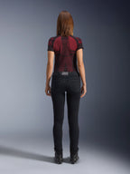 Alpinestars Daisy V3 Damen-Motorradjeans, Rinse Black, schmal geschnittene Motorradhose in der Rückansicht, mit High-Waist-Design und Gesäßtaschen, kombiniert mit einem rot-schwarz gemusterten Funktionsshirt und schwarzen Stiefeln, urbane Motorradausrüstung für Damen