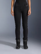 Alpinestars Banshee Damen-Leggings, schwarze Motorradhose, Slim-Fit-Design mit Akkordeon-Knieeinsätzen, getragen mit schwarzen High-Top-Motorradstiefeln, urbane Straßenausrüstung im lässigen Stil