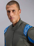 Alpinestars GP Race V3 Anzug FIA, Automobil-Rennanzug in Anthrazit-Blau, Nahaufnahme eines Models, die das Design des Oberteils mit blauen Schulter-Epauletten und weißen Alpinestars-Logos zeigt, professionelle Motorsportausrüstung.