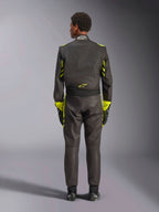 Alpinestars GP Race V3 Anzug FIA, Rückansicht, Schwarz mit gelben Fluo-Akzenten, mit gelben Einsätzen an Armen und Oberkörper, gelbes Logo am unteren Rücken, kombiniert mit passenden Rennhandschuhen und Stiefeln, professioneller Automobil-Rennanzug.