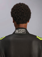 Alpinestars GP Race V3 Anzug FIA, Schwarz und Gelb Fluo, Nahaufnahme des hinteren Kragens mit dem FIA 8856-2018 Zertifizierungsetikett, professioneller Auto-Rennanzug.