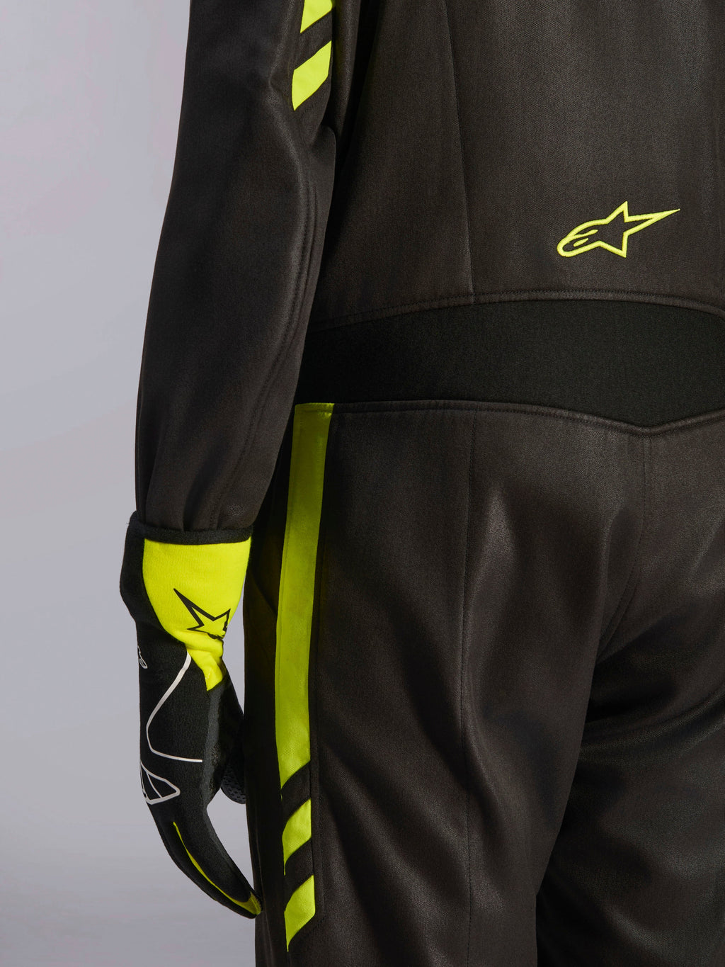 Alpinestars GP Race V3 Anzug FIA, Schwarz und Gelb Fluo, Nahaufnahme der Taille und des seitlichen Beins, mit Aramid-Stretcheinsätzen und passendem Rennhandschuh, professionelle Autorennsport-Ausrüstung