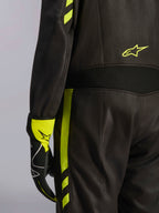 Alpinestars GP Race V3 Anzug FIA, Schwarz und Gelb Fluo, Nahaufnahme der Taille und des seitlichen Beins, mit Aramid-Stretcheinsätzen und passendem Rennhandschuh, professionelle Autorennsport-Ausrüstung