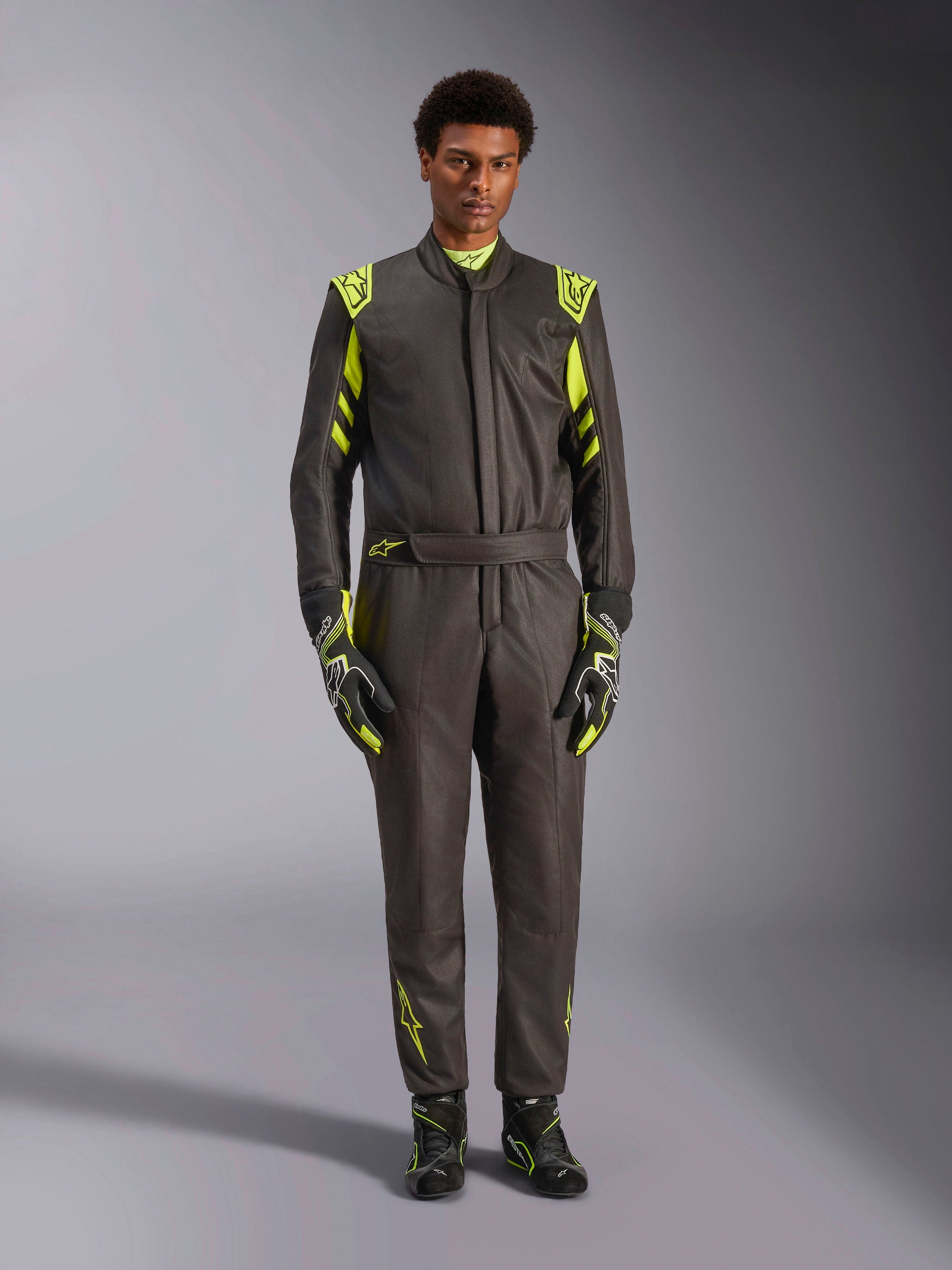 Alpinestars GP Race V3 Suit FIA, Auto Racing Suit, Black and Yellow Fluo, worn by a model with matching racing gloves and boots, featuring bright yellow accents on the shoulders, waist, and sleeves, professional motorsport gear