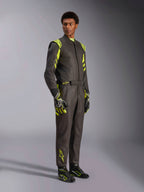 Alpinestars GP Race V3 Anzug FIA, Auto-Rennanzug, Schwarz und Fluo-Gelb, getragen von einem Model mit passenden Rennhandschuhen und Stiefeln, mit leuchtend gelben Akzenten an Schultern und Beinen, professionelle Motorsport-Ausrüstung