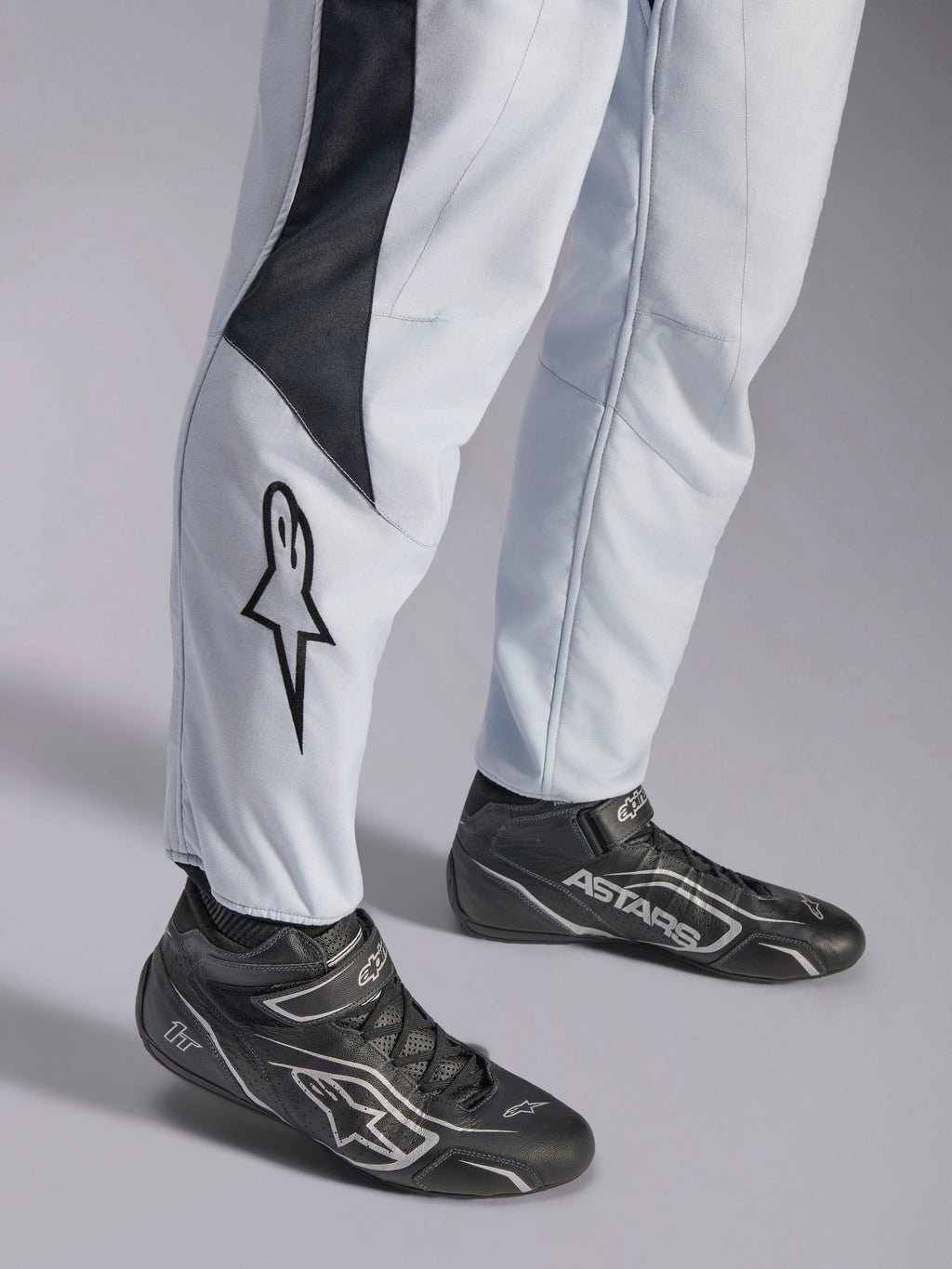 Alpinestars GP Pro Comp V2 FIA Suit, Gray and Black Auto Racing Suit with leg star logo and racing boots.