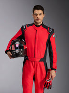 Männlicher Rennfahrer im Alpinestars GP Pro Comp V2 FIA Rennanzug in Rot und Schwarz, hält einen Carbon-Rennhelm und passende Handschuhe, professionelle Motorsport-Bekleidung