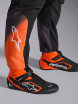 Close-up of Alpinestars KMX-5 V3 Suit legs, Black and Orange Fluo karting suit, featuring white logo on the calf, paired with matching black and orange professional racing shoes