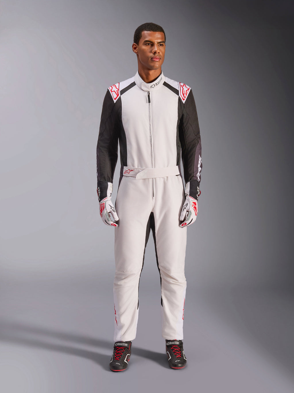 Alpinestars KMX-5 V3 Anzug, einteiliger Kart-Anzug, Weiß, Schwarz und leuchtendes Rot, getragen von einem Model mit passenden Rennhandschuhen und Schuhen, professionelle Motorsportausrüstung für den kompetitiven Kartsport