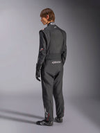Alpinestars GP Tech V4 Suit, Auto Racing Suit, Black with white accents, back view of model wearing the suit with racing gloves and shoes, featuring white branding on the lower back and leg, professional motorsport safety gear