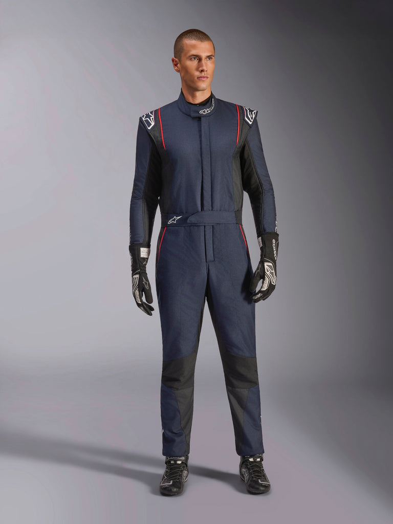 Alpinestars GP Tech V4 Anzug, professioneller Autorennanzug in Navyblau und Schwarz mit roten Paspeln, einteilige FIA-zertifizierte Rennausrüstung, getragen mit schwarzen Rennhandschuhen und Rennschuhen, Motorsport-Fahrerbekleidung
