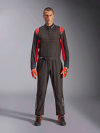 Alpinestars KMX-9 V3 Kart-Anzug, Schwarz und Fluo-Rot, einteiliger Rennanzug getragen mit farblich passenden Handschuhen und Stiefeln, mit leuchtend roten Schulterakzenten und Nähten, Alpinestars-Logo an den Unterschenkeln, schnittiges Motorsport-Design für den Rennsport