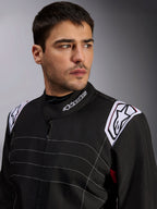 Alpinestars KMX-9 V3 Anzug, schwarzer Kart-Anzug, getragen von einem männlichen Model, Nahaufnahme von Brust und Schultern mit weißem Branding am Kragen und an den Epauletten, mit weißen Ziernähten und einem professionellen Motorsport-Design