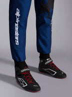 Alpinestars KMX-9 V3 Graphic 5 Anzug, Navy-Rot, Nahaufnahme der Unterschenkel und Kart-Schuhe, dunkelblaues Material mit weißem vertikalem Alpinestars-Schriftzug, schwarze Schuhe mit roten Schnürsenkeln und weißen Logos, professionelle Kart-Ausrüstung