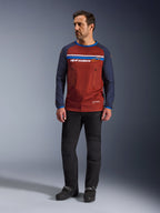Alpinestars Maxdura Dual Jersey, Rostbraun und Mood Indigo, Adventure-Motorradtrikot mit Mesh-Torso und dunkelblauen Ärmeln, getragen von einem Model mit schwarzer Fahrhose und schwarzen Stiefeln, technische Dual-Sport-Bekleidung für Offroad-Fahrten