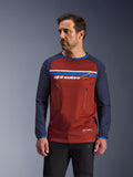Männliches Model trägt Alpinestars Maxdura Dual Jersey, Adventure-Motorradtrikot in Rostbraun und Marineblau, mit zwei Brusttaschen mit Reißverschluss, horizontalem Bruststreifen mit Branding, technischem Mesh-Torso und strapazierfähigen gewebten Ärmeln.