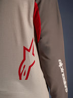 Alpinestars Maxdura Dual Jersey, Aluminum Walnut, Nahaufnahme des belüfteten Mesh-Torsos mit einem roten Stern-Logo und einem braunen, abriebfesten Ärmel mit weißem Alpinestars-Schriftzug, technische Adventure- und Dual-Sport-Motorradbekleidung