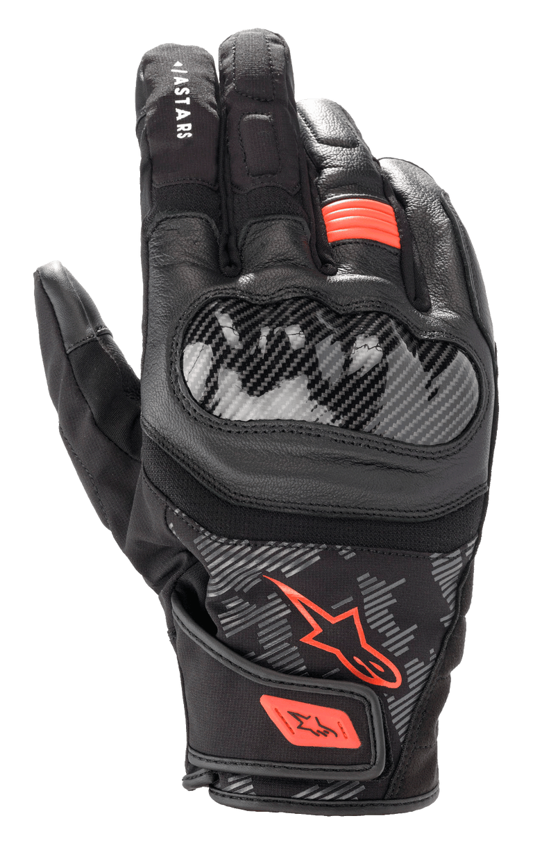 Displayed is the SMX Z Drystar® Glove by Alpinestars EU in a striking black and red fluo color combination. It features hard knuckle protectors, a Velcro wrist strap for secure fitting, and detailed stitching. This glove offers 100% waterproof protection, with extra padding on the index and middle fingers.