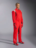 Alpinestars Kart Indoor V2 Anzug, roter Kart-Anzug, getragen von einem Model mit passenden rot-schwarzen Handschuhen und Schuhen, weiße Logos auf Schultern und Unterschenkel, schwarze Akzente, entwickelt für Freizeit-Kartfahren und Indoor-Strecken.