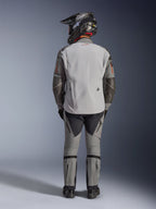 Alpinestars Nazca 3L GORE-TEX PRO Jacke, Adventure-Motorradjacke, Dunkelgrau und Mittelgrau, Rückansicht eines Fahrers in kompletter Ausrüstung, kombiniert mit passender Hose und schwarzem Adventure-Helm, mit rotem Logo auf dem Rücken und Superfabric-Verstärkungen an den Ellbogen, strapazierfähiges Textildesign für Adventure-Touren.