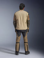 Alpinestars Nazca 3L GORE-TEX PRO Jacke in Walnut Rock Brown, Rückansicht des Fahrers, zeigt Superfabric-Verstärkungen an den Ellbogen und hintere Belüftungsreißverschlüsse, getragen mit passender Adventure-Hose, schwarzen Stiefeln und Handschuhen, robuste technische Fahrbekleidung für extreme Abenteuer.