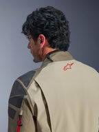 Alpinestars Nazca 3L GORE-TEX PRO Jacke, Walnut Rock Brown Adventure-Jacke, Nahaufnahme von Rücken und Schulter, rotes Stern-Logo am Nacken, graue strukturierte Verstärkungspanele, strapazierfähige Textilkonstruktion für das Motorradfahren