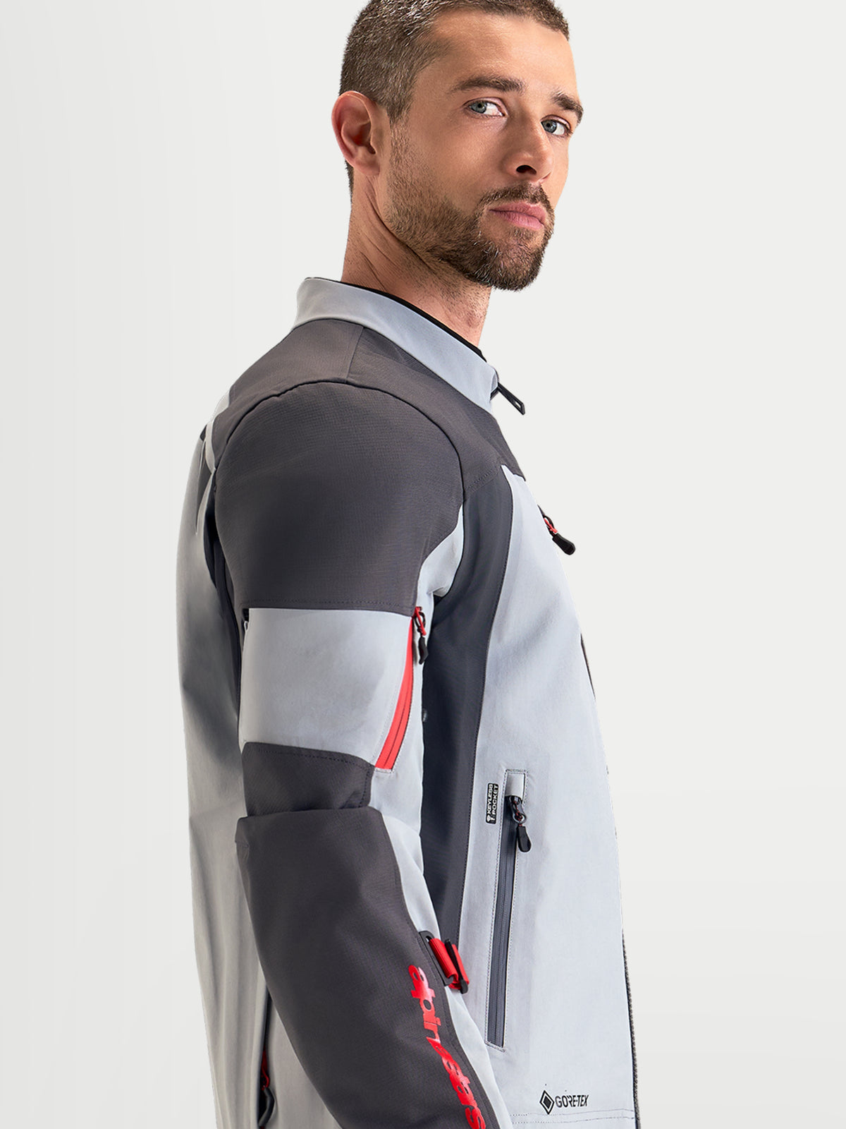 Alpinestars Arenis Gore-Tex Jacke, Herren-Adventure-Motorradjacke in Mittelgrau, Dunkelgrau und Schwarz, Seitenansicht an Model mit wasserdichter Textilkonstruktion und ergonomischem Kragen