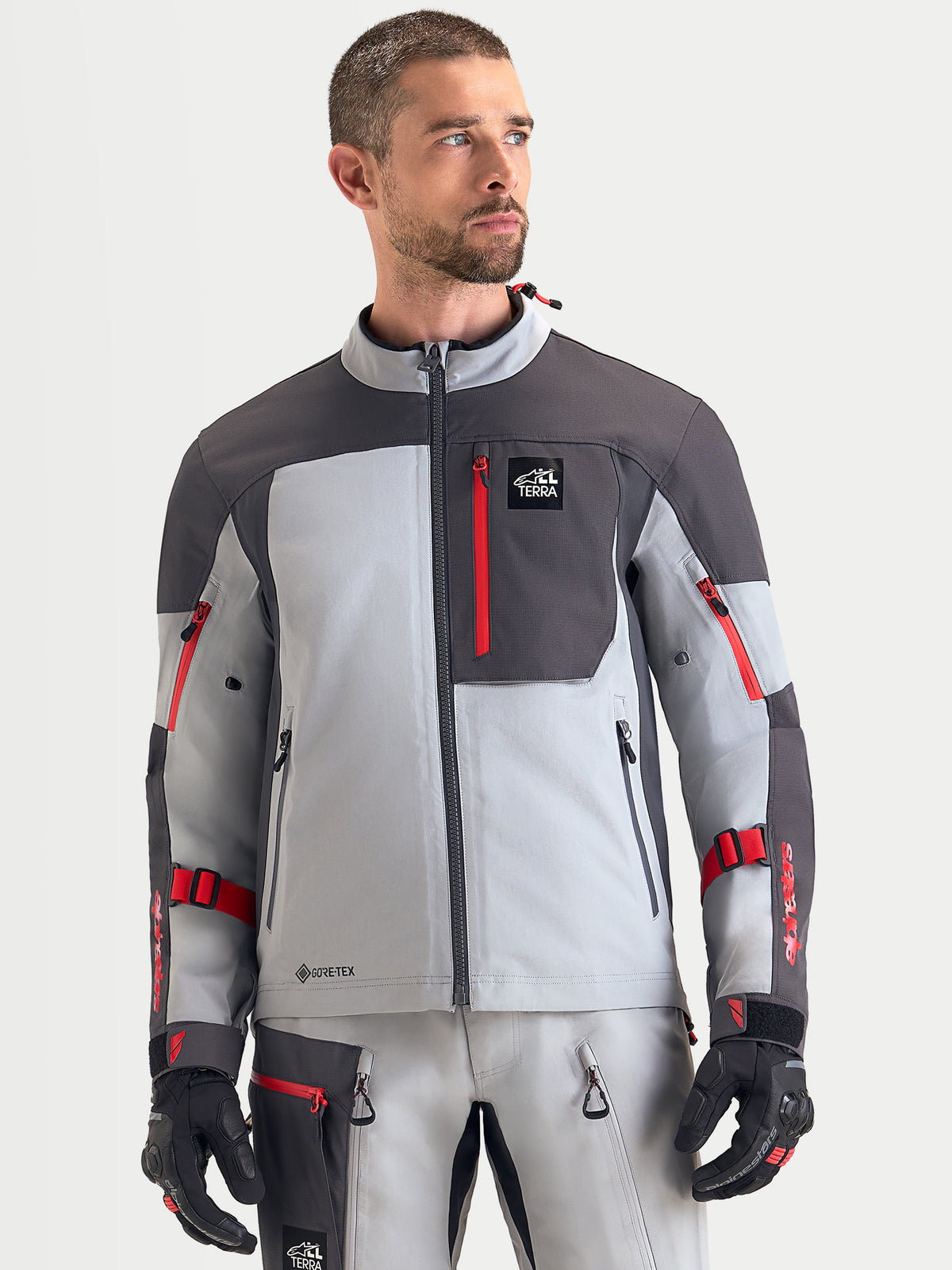 Alpinestars Arenis Gore Tex Jacke, Herren-Adventure-Motorradjacke in Mittelgrau, Dunkelgrau und Schwarz, Vorderansicht an einem Model, mit wasserdichter Gore-Tex-Konstruktion und Reißverschluss-Brusttasche