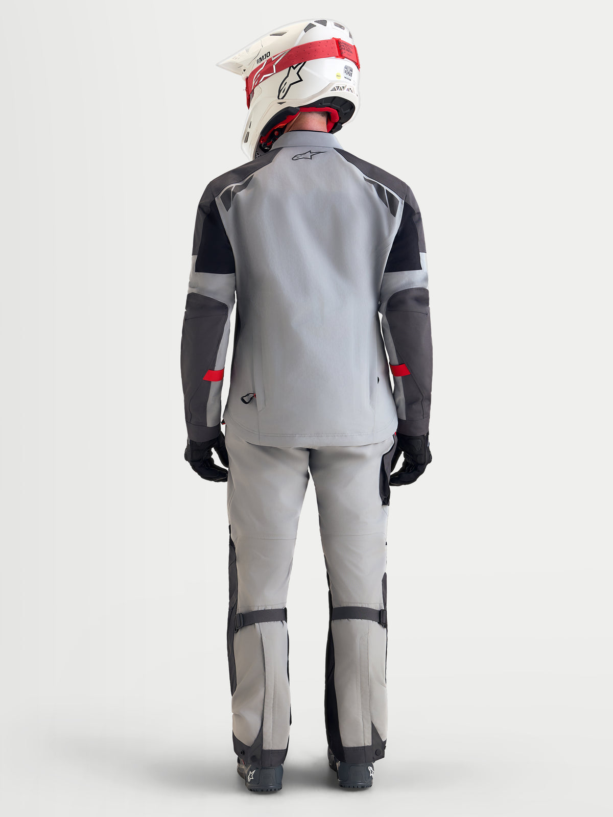 Alpinestars Arenis Gore Tex Jacke, Herren-Adventure-Motorradjacke in Mittelgrau, Dunkelgrau und Schwarz, Rückansicht des Modells mit wasserdichter Textiljacke, Helm und Schutzausrüstung