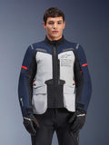 Alpinestars ST-7 2L GORE-TEX Jacke, Motorrad-Adventure-Touringjacke, Eisgrau und Dunkelblau mit roten Akzenten, wasserdicht und atmungsaktiv, getragen von einem Modell mit schwarzen Handschuhen, mit Alpinestars Exploration Equipment Branding auf der Brust