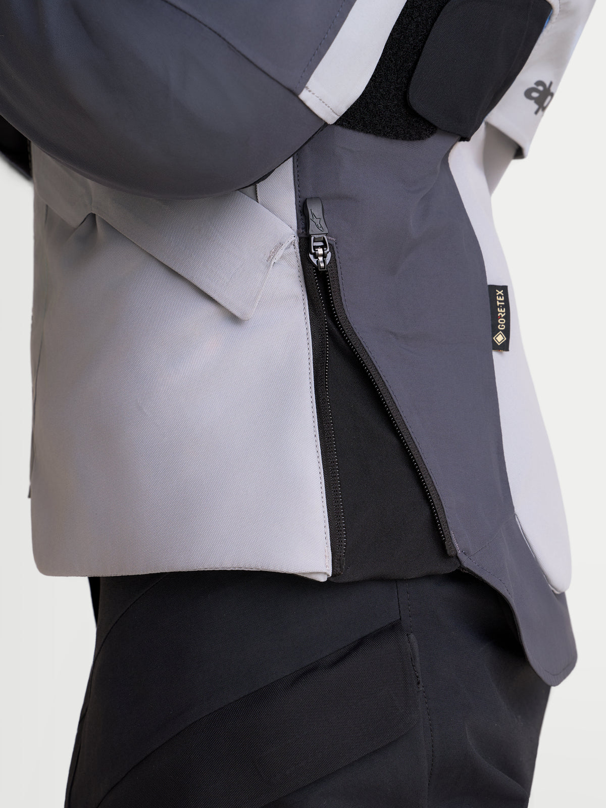 Alpinestars Stella St-7 V2 2L Gore-Tex® Jacket, women's adventure touring motorcycle jacket in mid gray, deep gray, and black, detailed close-up view showing the side zipper and waterproof textile construction.