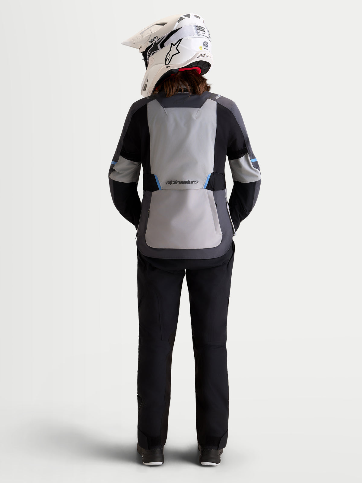Alpinestars Stella ST-7 V2 2L Gore-Tex Jacket, women's all-terrain adventure touring motorcycle jacket in mid gray, deep gray, and black, rear profile view on a model wearing matching gear and helmet, waterproof textile construction.