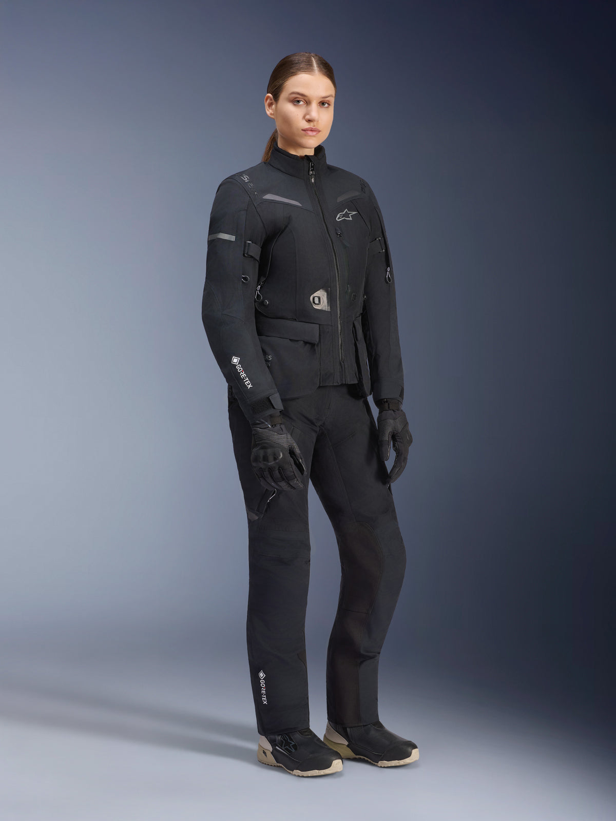 Alpinestars Stella ST-7 2L GORE-TEX Damenjacke, Schwarz, getragen mit passender Motorradhose und Handschuhen, Adventure-Road-Touring-Ausrüstung mit laminiertem GORE-TEX-Branding am Ärmel und taillierter Damenpassform.
