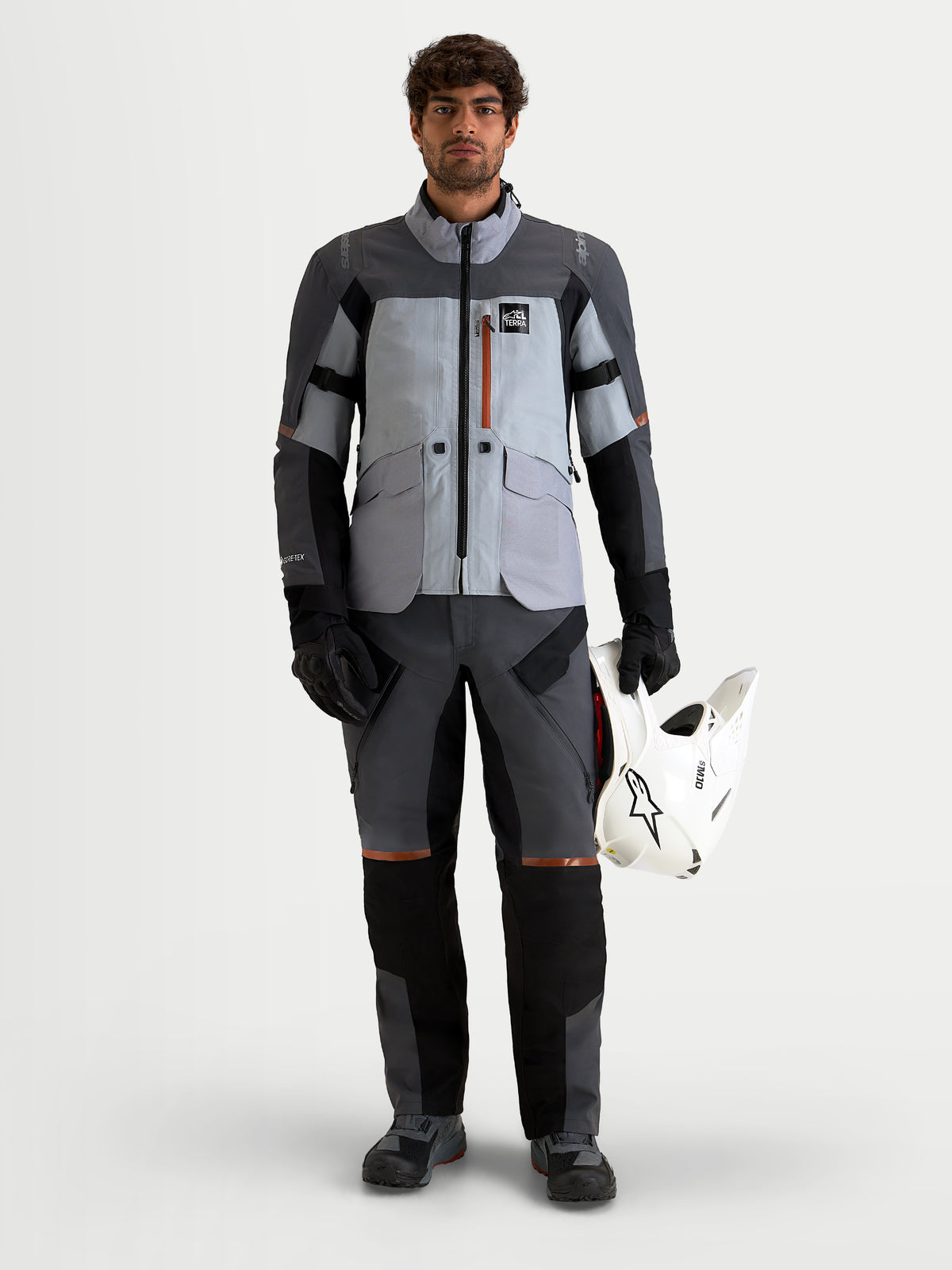 Alpinestars St-7 V2 2L Gore-Tex Pants, men's adventure touring motorcycle pants in deep gray and black, front full-length view on a model wearing matching gear and holding a helmet.
