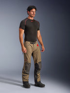 Alpinestars Nazca 3L GORE-TEX PRO Hose in Walnut Black, Adventure-Motorradhose mit schwarzen Superfabric-Verstärkungen an den Knien, getragen von einem Modell mit schwarzem Kompressions-Base-Layer, ausgestattet mit einem Gürtel mit Magnetschnalle und rotem All Terra Branding.