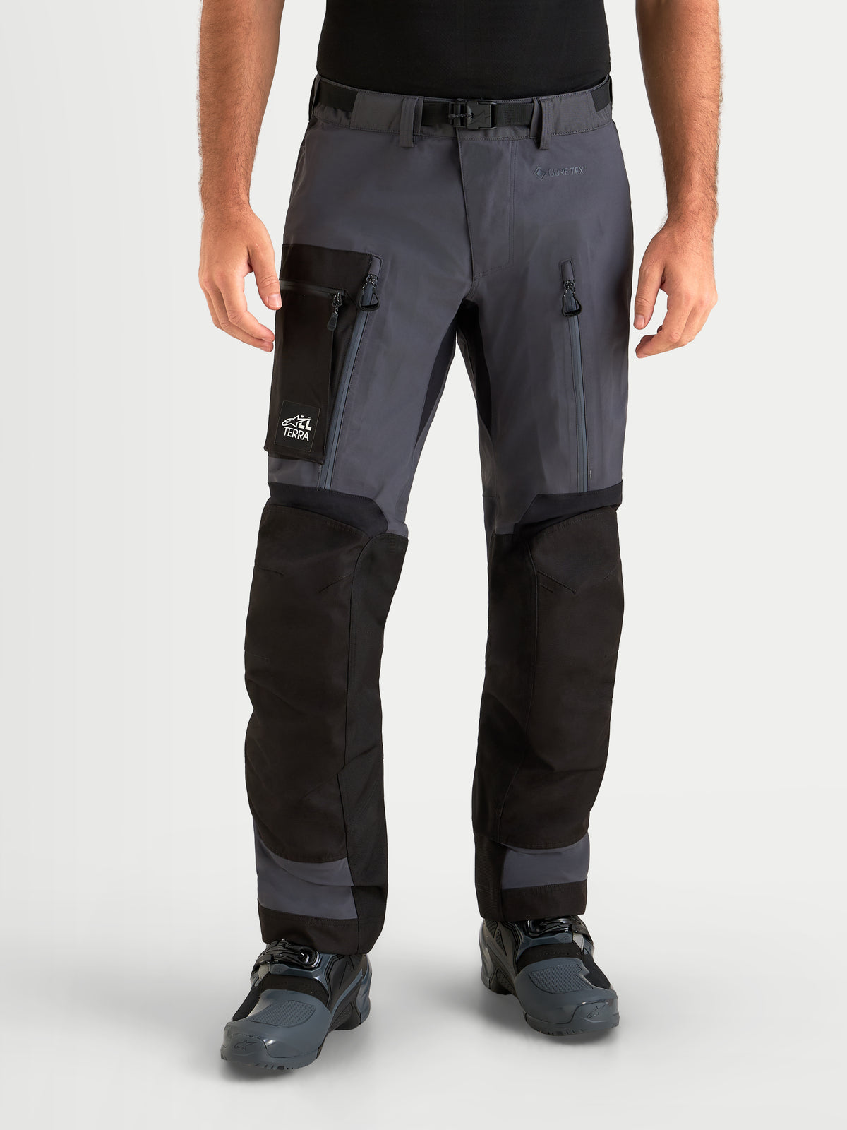 Alpinestars Arenis Gore-Tex Hose, Herren-Adventure-Motorradhose in Schwarz und Dunkelgrau, Vorderansicht am Model mit Cargo-Taschen und Oberschenkelbelüftung, wasserdichte Textil-Ruhrausrüstung
