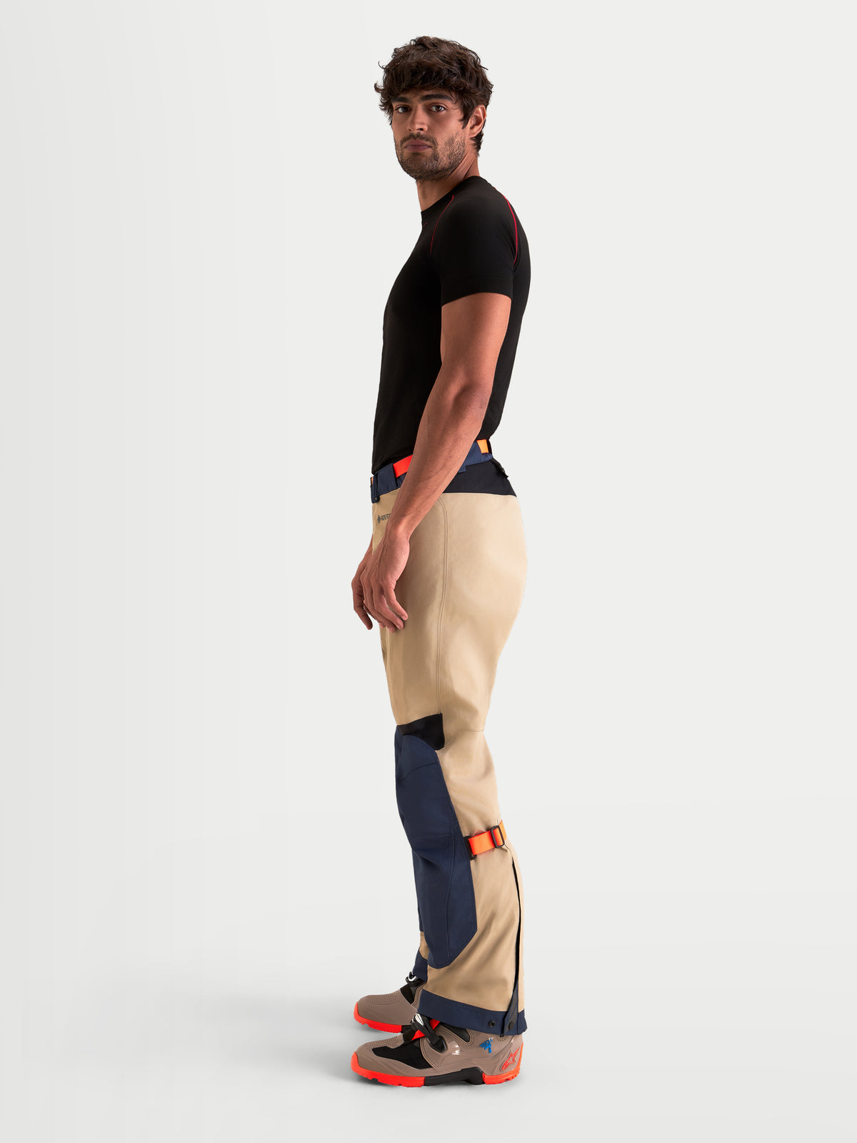 Alpinestars Arenis Gore-Tex Hose, Herren-Abenteuer-Motorradhose in Marineblau und Aluminium, Seitenprofilansicht an Model mit wasserdichter Textilkonstruktion und Unterschenkel-Passformverstellern