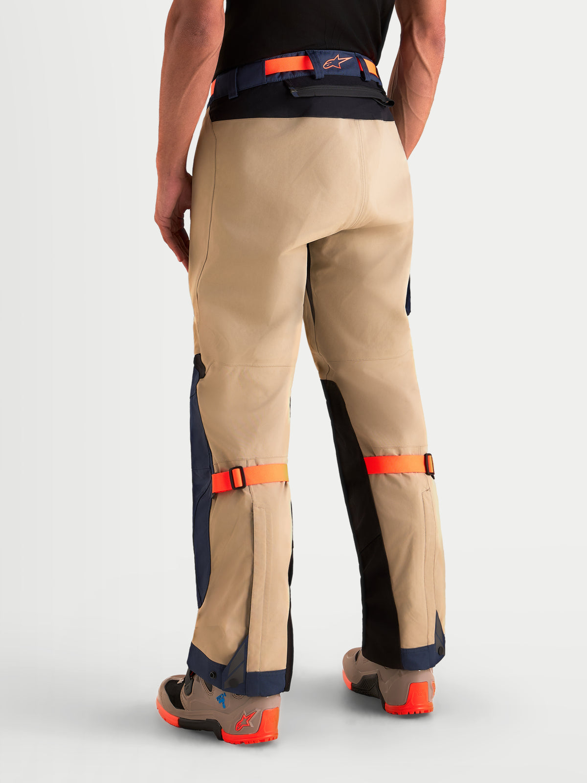 Alpinestars Arenis Gore-Tex Hose, Herren-Abenteuer-Motorradhose in Beige, Marineblau und Orange, Rückansicht an einem Model mit wasserdichter Textilkonstruktion, verstärktem Sitzbereich und verstellbaren Riemen.
