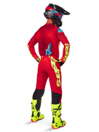 Alpinestars 2025 Supertech Maker Hose, Motocross-Hose, Hellrot und Neongelb, Rückansicht eines Fahrers in passendem rotem Trikot, fluoreszierend gelbe Stiefel und schwarzer Helm, mit großem gelben Alpinestars-Branding am Bein.