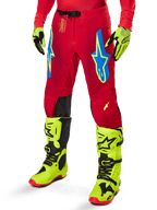 Alpinestars 2025 Supertech Maker Hose, Motocross-Hose, leuchtendes Rot mit blauen und gelben Stern-Logos, schwarze Knieeinsätze, perforierte Belüftung, kombiniert mit neongelben Stiefeln und Handschuhen