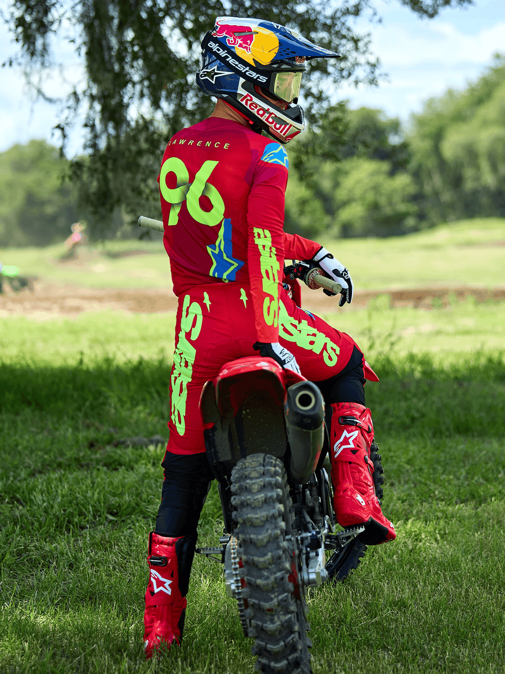 Motocross-Fahrer im Alpinestars 2025 Supertech Maker Ausrüstungsset in Hellrot und Gelb Fluo, sitzend auf einem roten Dirtbike, mit der Trikotnummer 96, passenden roten Stiefeln und Helm, professionelle Rennausrüstung für Offroad-Performance
