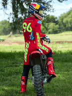 Motocross-Fahrer auf einem roten Dirtbike, Alpinestars 2025 Supertech Maker Hose in Bright Red und Yellow Fluo, passendes rotes Trikot mit „96“ und „LAWRENCE“ auf dem Rücken, rote Rennstiefel und ein Helm mit Red Bull-Branding, professionelles Offroad-Rennausrüstungsset