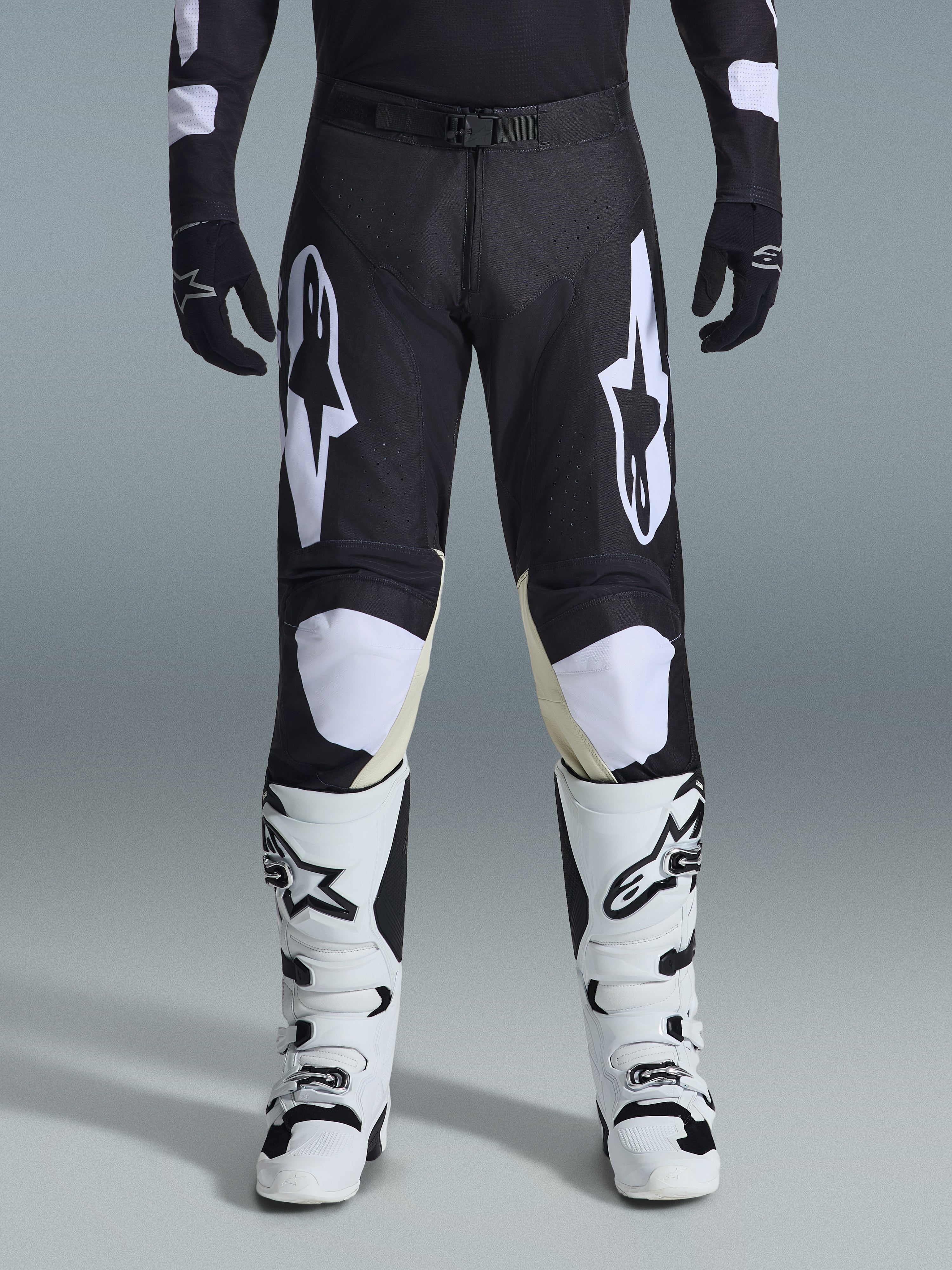 Alpinestars 2026 Racer Air Riway Hose, Motocross-Hose, Schwarz und Weiß, mit markanten weißen Alpinestars-Logos an den Oberschenkeln und Knie-Einsätzen, kombiniert mit weiß-schwarzen Motocross-Stiefeln und schwarzen Handschuhen, athletische Rennpassform für den Offroad-Sport