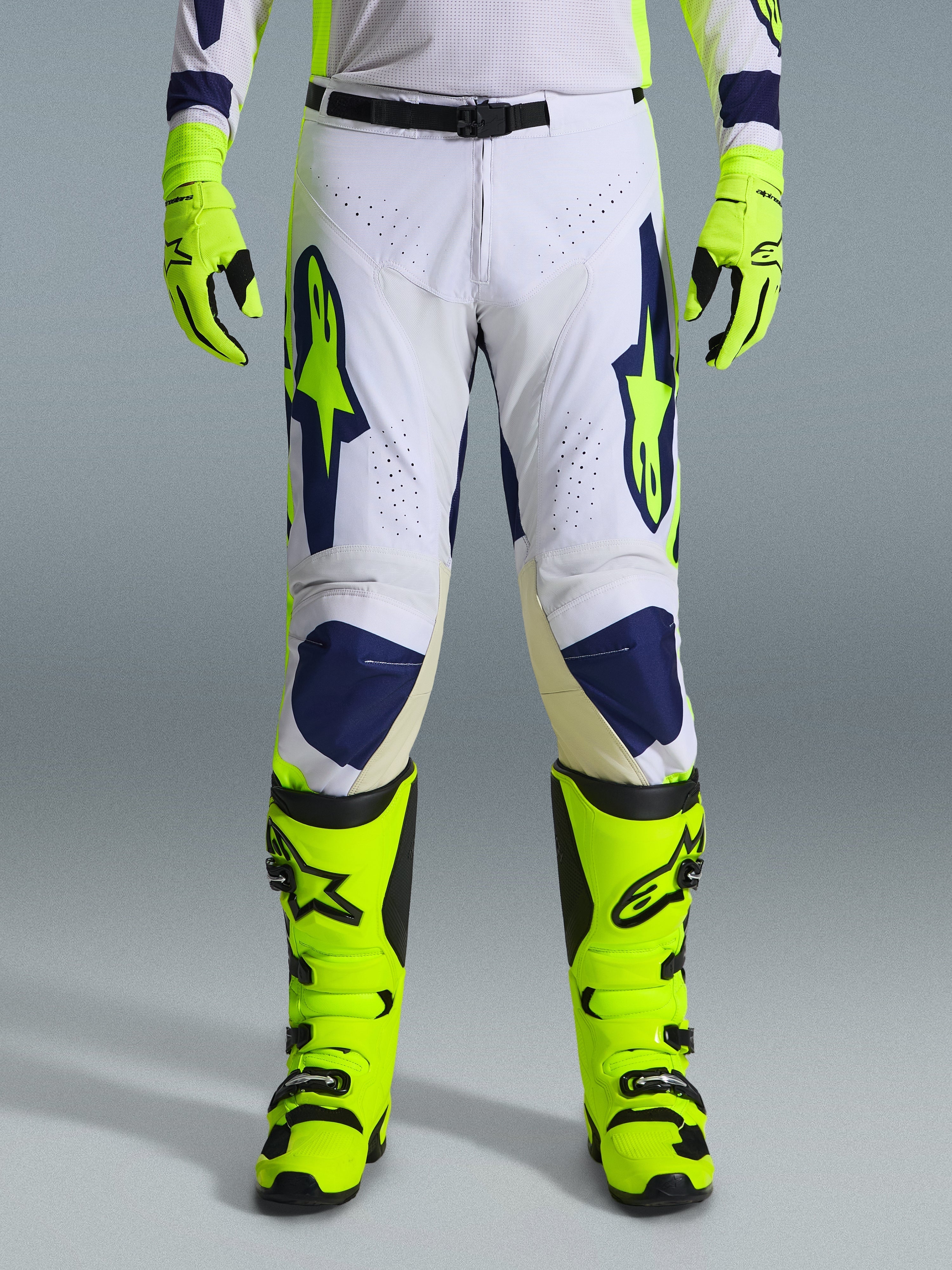 Alpinestars 2026 Racer Air Riway Hose, Motocross-Hose, Hellgrau, Gelb Fluo und Blau, getragen mit passenden neongelben Handschuhen und Stiefeln, ausgestattet mit perforierten Vorderseiten für optimale Belüftung und markantem blau-gelbem Branding, athletisches Design für Offroad-Performance
