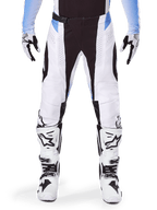Alpinestars 2025 Techstar Melt Hose, Motocross-Hose, Weiß und Schwarz mit hellblauen Akzenten, getragen mit passenden weißen und schwarzen Stiefeln und Handschuhen, mit lasergeschnittenen Perforationen und Hochleistungs-Renndesign.