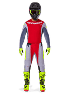 Motocross-Fahrer mit Alpinestars 2025 Techstar Melt Hose in Hellrot und Grau, mit leuchtend roten Einsätzen und neongelben Akzenten, kombiniert mit passendem Trikot, schwarzem Helm mit neongelber Brille sowie leuchtend gelben Stiefeln und Handschuhen, abgestimmtes Outfit für professionellen Motocross-Rennsport.