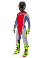 Motocross-Fahrer in kompletter Rennausrüstung, rotes und graues Trikot mit Alpinestars-Branding, 2025 Techstar Melt Hose in Hellrot und Grau mit neon-gelben Akzenten, leuchtend gelbe Stiefel und Handschuhe, schwarzer Helm mit neon-gelber Brille, koordiniertes Outfit für Offroad-Performance.